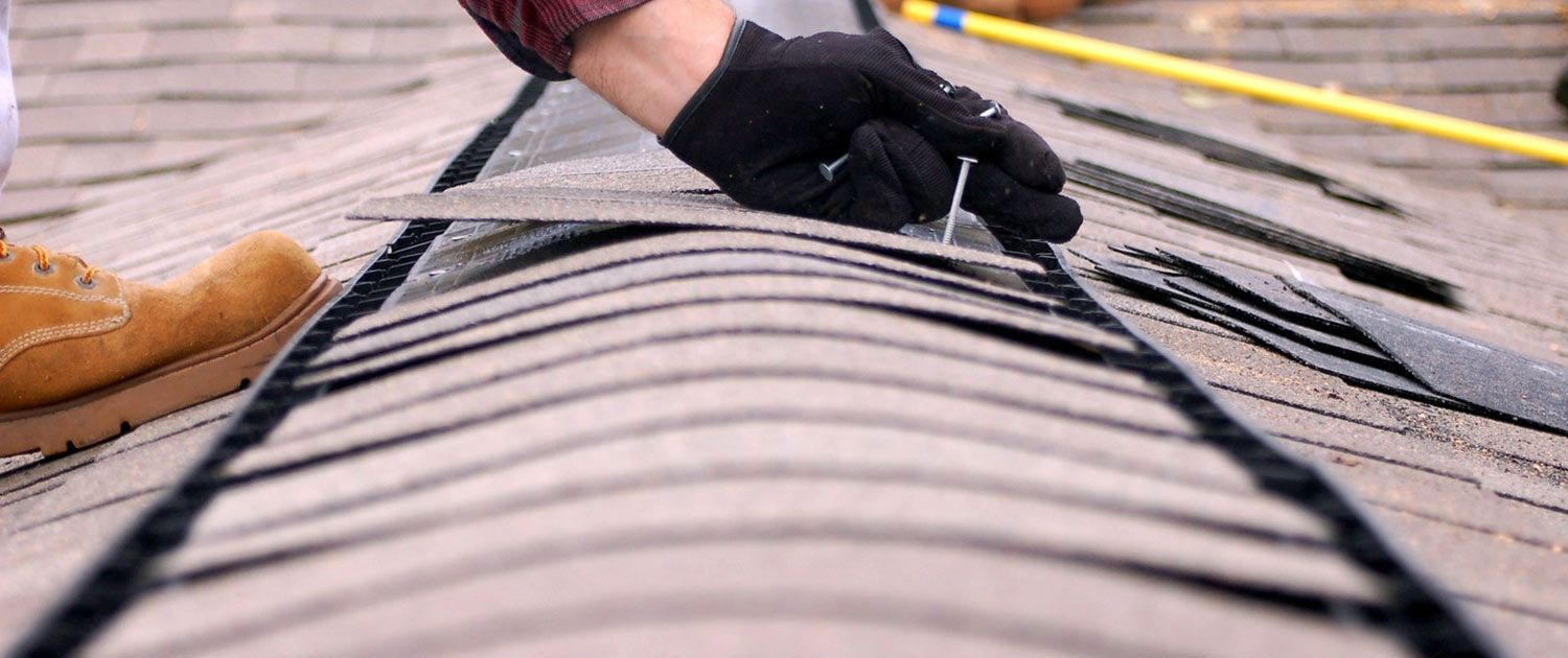 A professional roofer repairs shingles on a roof